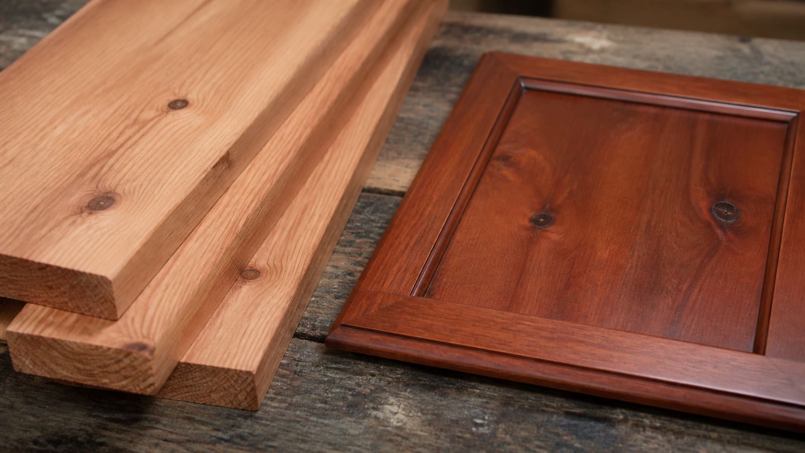Close-up of pale reddish alder lumber showing fine grain and dark cabinet-grade knots